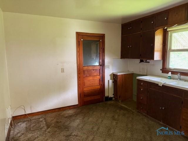 600 Tiedeman Ave, Defiance, OH 43512 - kitchen featuring a sink, light countertops, dark colored carpet, radiator heating unit, and dark brown cabinets