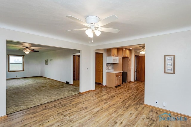 16470 County Road P, Napoleon, OH 43545 - unfurnished living room with a ceiling fan, light wood finished floors, and baseboards