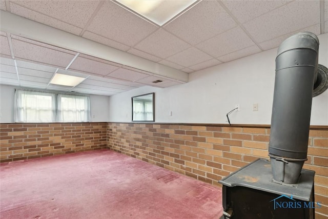 146 Partridge Ln, Perrysburg, OH 43551 - below grade area with a drop ceiling, a wainscoted wall, brick wall, a wood stove, and carpet floors