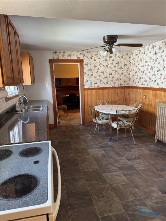 108 E Maple St, Deshler, OH 43516 - kitchen featuring electric range, wainscoting, a sink, brown cabinets, and ceiling fan