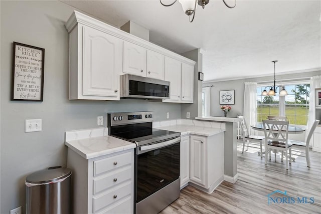1250 Indiana Ave, Napoleon, OH 43545 - kitchen with appliances with stainless steel finishes, a chandelier, white cabinetry, light wood-type flooring, and light stone counters