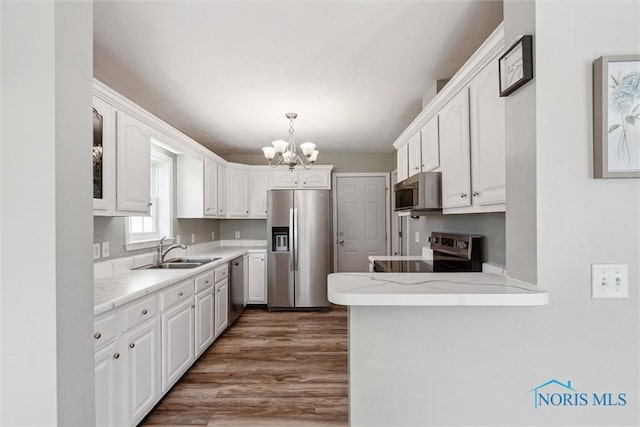 1250 Indiana Ave, Napoleon, OH 43545 - kitchen with stainless steel appliances, a sink, a chandelier, white cabinets, and wood finished floors