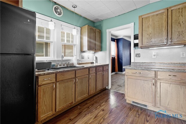 1006 Woodward Ave, Toledo, OH 43608 - kitchen featuring freestanding refrigerator, a sink, dark wood finished floors, hanging light fixtures, and brown cabinetry