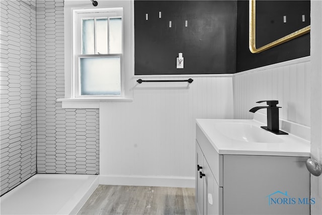 1006 Woodward Ave, Toledo, OH 43608 - full bath featuring vanity, a wainscoted wall, wood finished floors, and a tile shower
