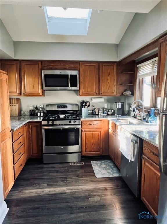 5806 Elmer Dr, Toledo, OH 43615 - kitchen featuring stainless steel appliances, dark wood finished floors, a skylight, brown cabinets, and light stone counters