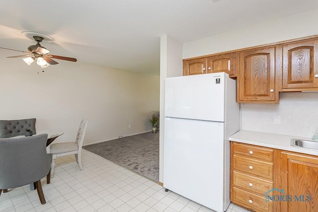 1201 Birch Ave, Maumee, OH 43537 - kitchen featuring freestanding refrigerator, ceiling fan, light colored carpet, light countertops, and brown cabinets