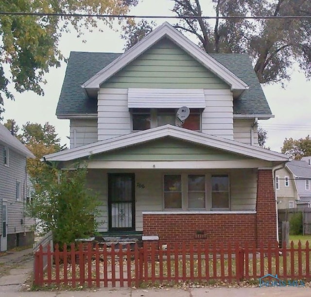 766 Spencer St, Toledo, OH 43609 - traditional style home featuring covered porch, a fenced front yard, brick siding, and roof with shingles
