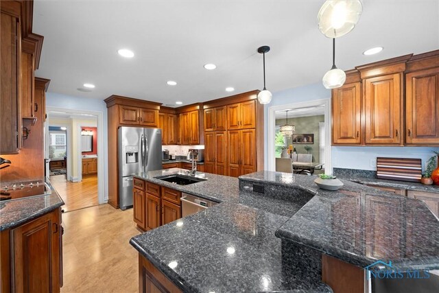 26741 Green Ville Dr, Perrysburg, OH 43551 - kitchen featuring appliances with stainless steel finishes, a sink, pendant lighting, dark stone counters, and brown cabinetry