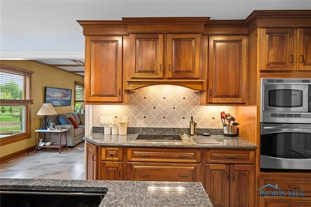 26741 Green Ville Dr, Perrysburg, OH 43551 - kitchen featuring stainless steel microwave, brown cabinetry, backsplash, and dark stone counters