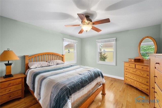 26741 Green Ville Dr, Perrysburg, OH 43551 - bedroom featuring multiple windows, baseboards, light wood-style flooring, and ceiling fan