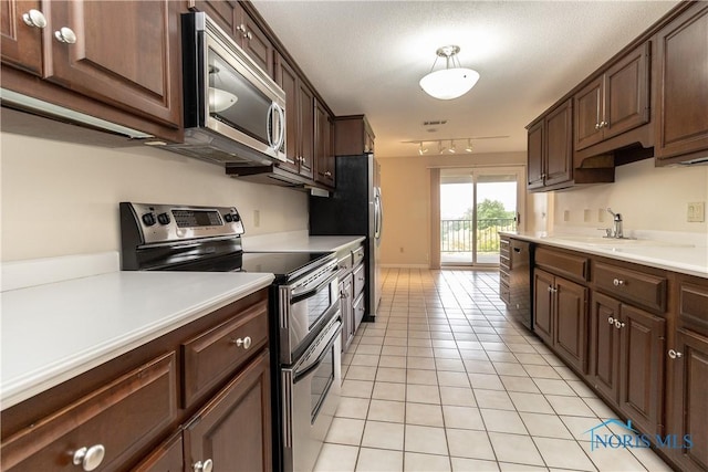 5831 Monroe St Unit 602, Sylvania, OH 43560 - kitchen with appliances with stainless steel finishes, light tile patterned floors, a sink, light countertops, and dark brown cabinetry