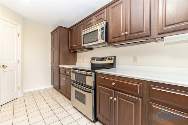 5831 Monroe St Unit 602, Sylvania, OH 43560 - kitchen featuring stainless steel appliances, light tile patterned flooring, light countertops, baseboards, and dark brown cabinetry