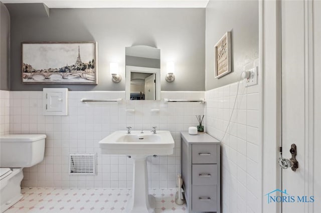 2256 Barrington Dr, Toledo, OH 43606 - half bathroom with toilet, a sink, tile walls, and wainscoting