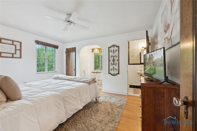 2256 Barrington Dr, Toledo, OH 43606 - bedroom featuring arched walkways, light wood-style floors, connected bathroom, baseboards, and ceiling fan