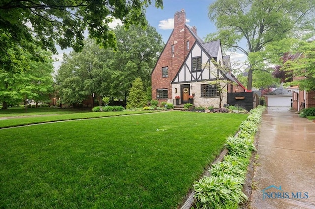 2256 Barrington Dr, Toledo, OH 43606 - tudor home with a front yard, stone siding, a chimney, an outbuilding, and a detached garage
