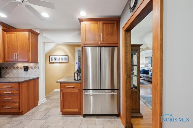 2256 Barrington Dr, Toledo, OH 43606 - kitchen with freestanding refrigerator, decorative backsplash, dark stone countertops, ceiling fan, and brown cabinetry