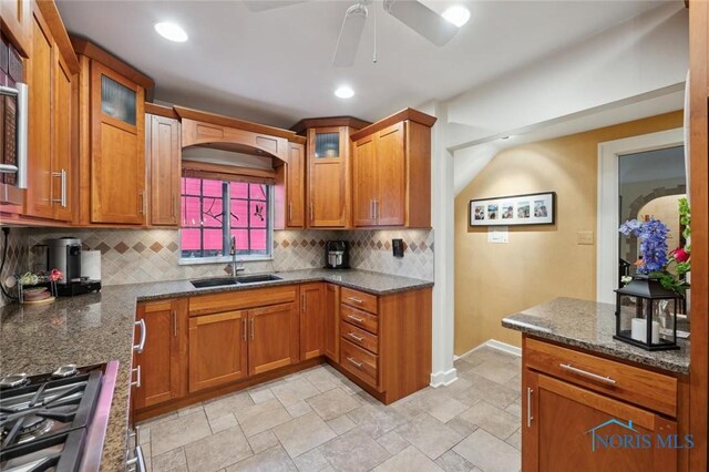 2256 Barrington Dr, Toledo, OH 43606 - kitchen with a sink, backsplash, dark stone countertops, brown cabinets, and recessed lighting