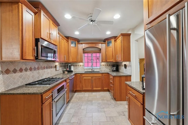 2256 Barrington Dr, Toledo, OH 43606 - kitchen with stainless steel appliances, a sink, light stone finish floors, brown cabinets, and a ceiling fan