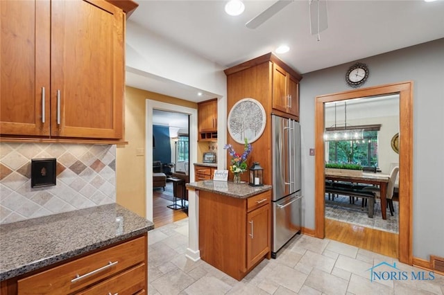 2256 Barrington Dr, Toledo, OH 43606 - kitchen with freestanding refrigerator, brown cabinetry, dark stone countertops, decorative backsplash, and recessed lighting