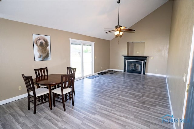 1500 S Jackson Ave, Defiance, OH 43512 - dining room with wood finished floors, a glass covered fireplace, a ceiling fan, baseboards, and high vaulted ceiling