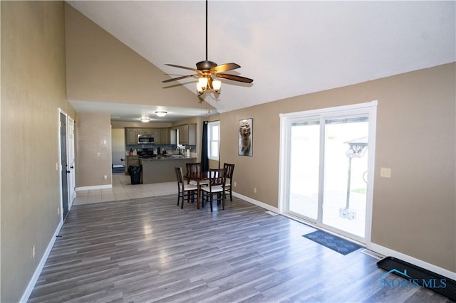 1500 S Jackson Ave, Defiance, OH 43512 - dining space featuring baseboards, a ceiling fan, light wood-type flooring, and high vaulted ceiling
