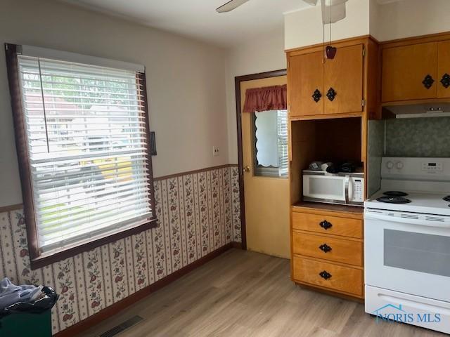 925 S Cherry St, Bryan, OH 43506 - kitchen featuring white appliances, wallpapered walls, light wood finished floors, wainscoting, and under cabinet range hood