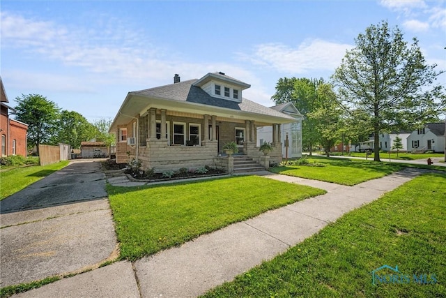 451 Toledo St, Elmore, OH 43416 - bungalow featuring asphalt driveway, covered porch, a front yard, stone siding, and a chimney