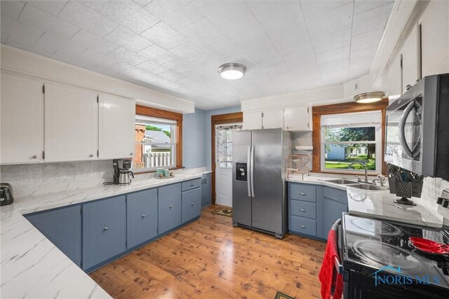 451 Toledo St, Elmore, OH 43416 - kitchen featuring appliances with stainless steel finishes, white cabinets, a sink, blue cabinets, and decorative backsplash