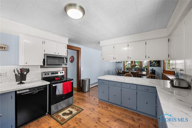 451 Toledo St, Elmore, OH 43416 - kitchen featuring appliances with stainless steel finishes, white cabinetry, light stone counters, light wood-style flooring, and baseboard heating