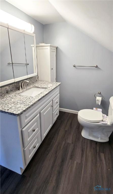 2621 Gloria Ct, Toledo, OH 43614 - bathroom featuring wood finished floors, vaulted ceiling, vanity, toilet, and baseboards