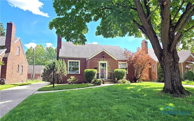 2621 Gloria Ct, Toledo, OH 43614 - view of front of home featuring brick siding, a front yard, a chimney, roof with shingles, and concrete driveway