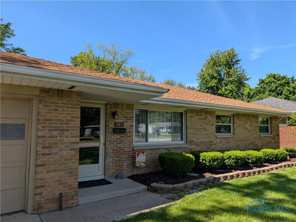 243 W S Boundary St, Perrysburg, OH 43551 - doorway to property with brick siding, a shingled roof, and a yard