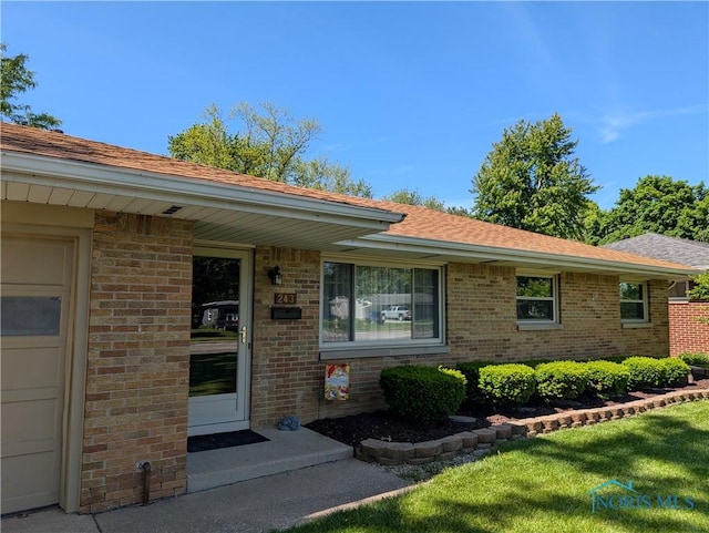 243 W S Boundary St, Perrysburg, OH 43551 - doorway to property with brick siding, a shingled roof, and a yard