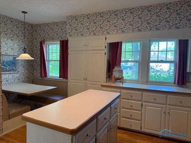 743 E Lincoln St, Findlay, OH 45840 - kitchen with wallpapered walls, white cabinetry, light countertops, light wood-type flooring, and decorative light fixtures