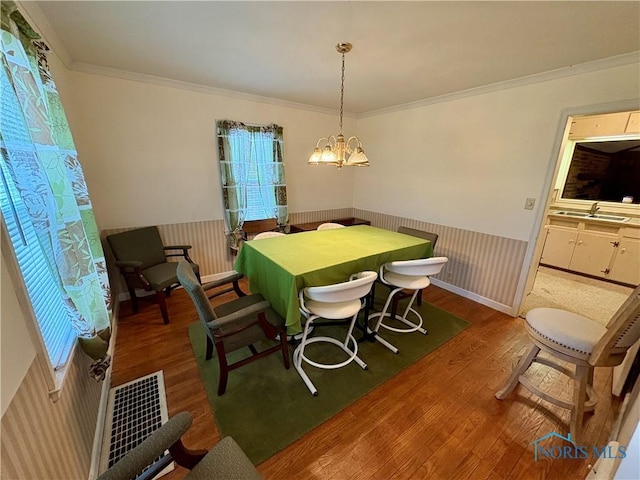 178 Gross St, Tiffin, OH 44883 - dining area featuring wood finished floors, healthy amount of natural light, a wainscoted wall, ornamental molding, and a chandelier