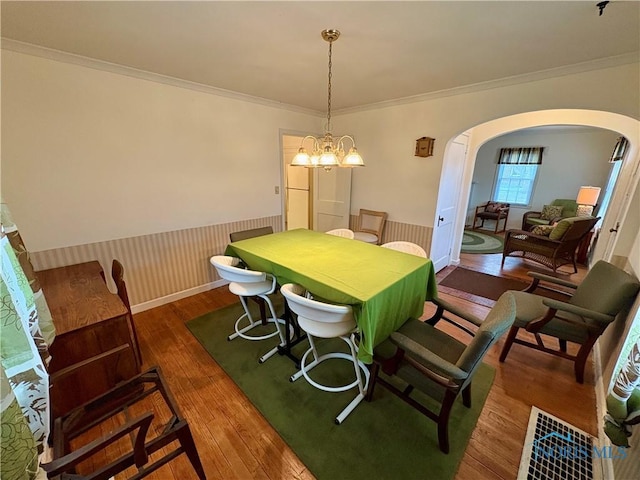 178 Gross St, Tiffin, OH 44883 - dining area featuring arched walkways, wainscoting, wood finished floors, crown molding, and a chandelier