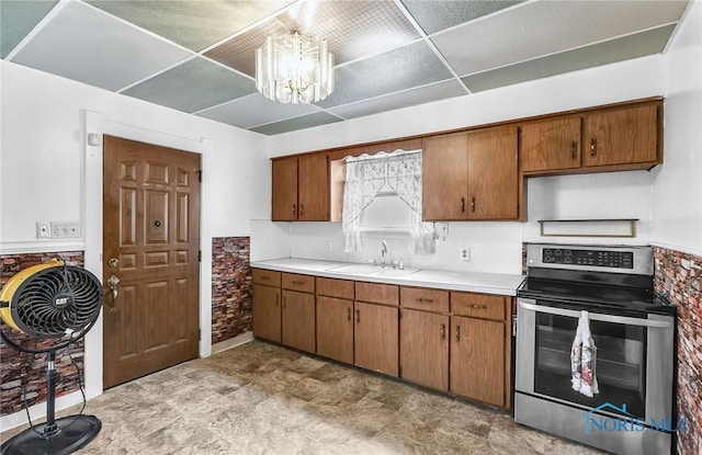 358 Burger St, Toledo, OH 43605 - kitchen with stainless steel range with electric cooktop, brown cabinetry, light countertops, a chandelier, and a drop ceiling