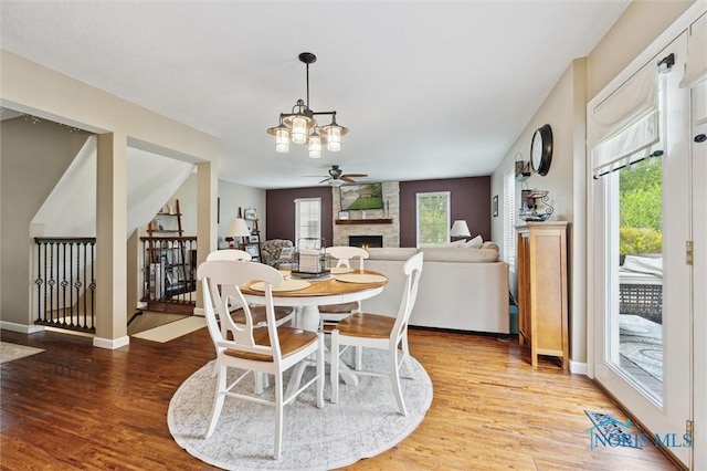 6200 Swiss Garden Rd, Toledo, OH 43612 - dining room with a stone fireplace, light wood-style floors, ceiling fan, and healthy amount of natural light