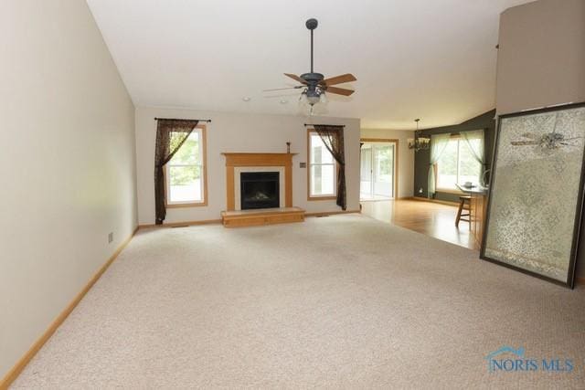 1033 Joseph Rd, Luckey, OH 43443 - unfurnished living room featuring carpet, a ceiling fan, a fireplace with raised hearth, a chandelier, and baseboards