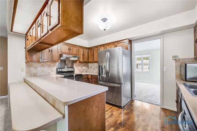 1 Hawthorne Dr, Delta, OH 43515 - kitchen featuring stainless steel appliances, under cabinet range hood, dark wood-style flooring, light countertops, and a peninsula