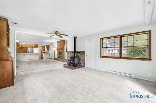 1 Hawthorne Dr, Delta, OH 43515 - unfurnished living room featuring baseboard heating, a wood stove, a ceiling fan, carpet floors, and beam ceiling