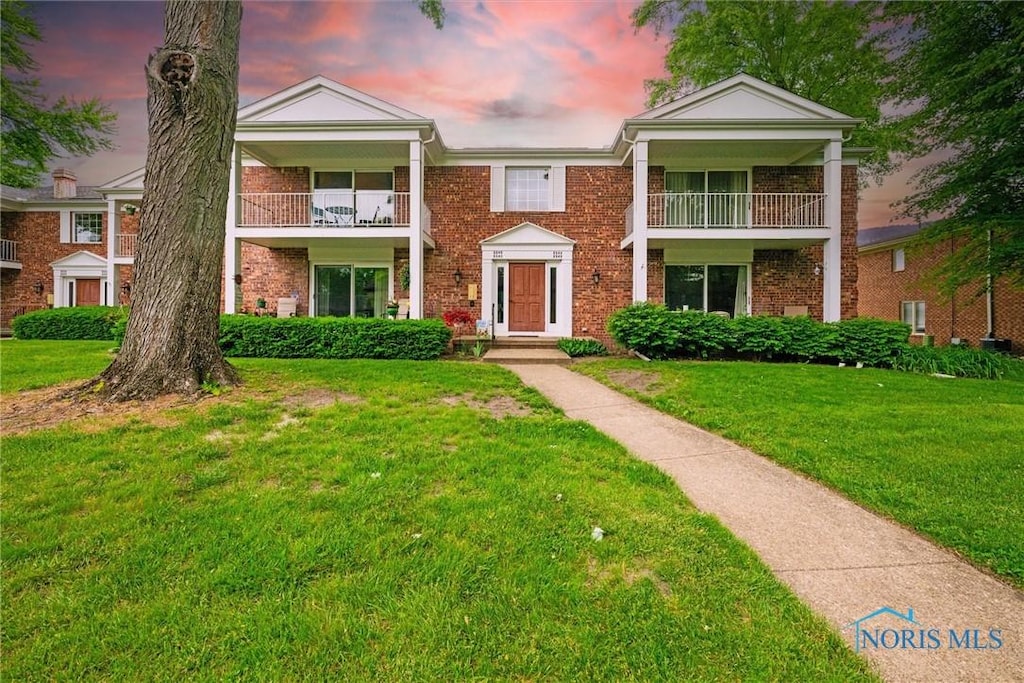 6546 Abbey Run Unit 7, Sylvania, OH 43560 - neoclassical home with a balcony, brick siding, and a front lawn