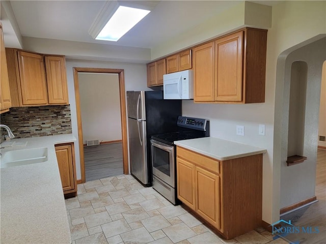 3434 Muirfield Ave, Toledo, OH 43614 - kitchen featuring stainless steel appliances, a sink, light countertops, backsplash, and arched walkways