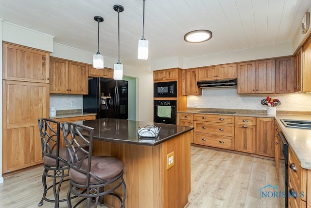 12949 Shaffer Rd, Swanton, OH 43558 - kitchen with black appliances, under cabinet range hood, light wood finished floors, a breakfast bar area, and tasteful backsplash