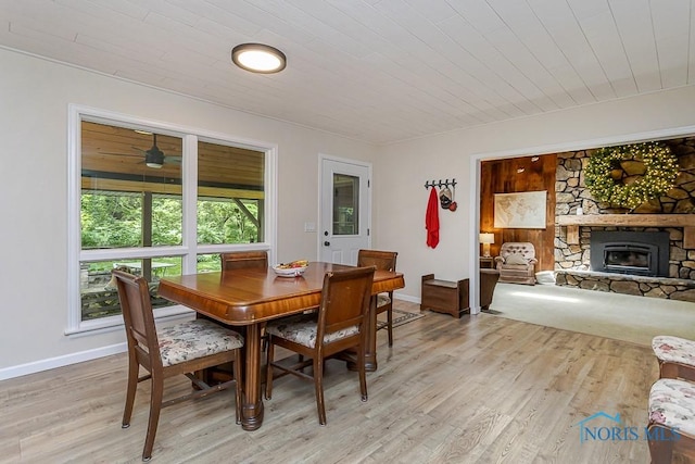 12949 Shaffer Rd, Swanton, OH 43558 - dining space featuring light wood-type flooring, wood ceiling, a stone fireplace, and baseboards