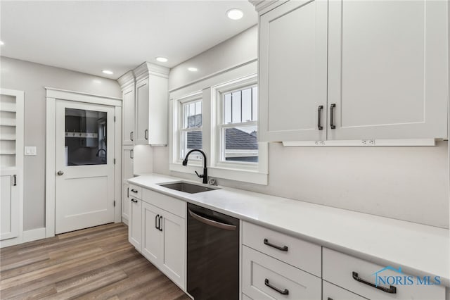 430 E 3rd St, Ottawa, OH 45875 - kitchen with dishwasher, a sink, light countertops, light wood-style floors, and white cabinetry