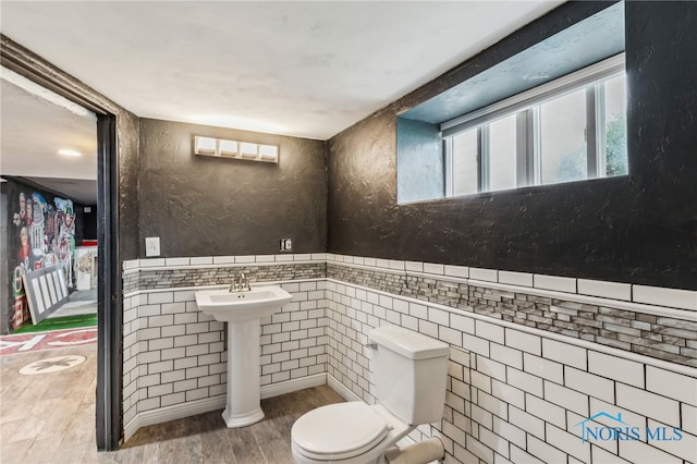 430 E 3rd St, Ottawa, OH 45875 - half bathroom with tile walls, toilet, wood finished floors, a sink, and wainscoting