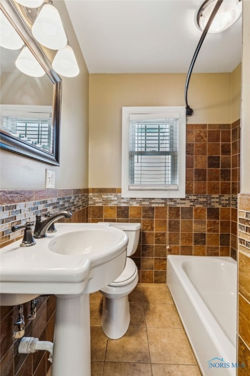 430 E 3rd St, Ottawa, OH 45875 - bathroom featuring tile walls, toilet, tile patterned flooring, shower / bathtub combination, and a wainscoted wall