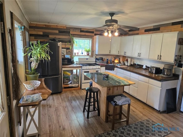 201 W Wabash St, Liberty Center, OH 43532 - kitchen featuring white gas range, freestanding refrigerator, dark countertops, crown molding, and light wood-style flooring