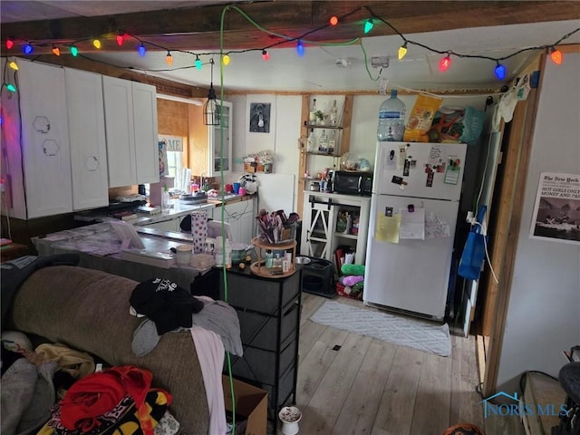201 W Wabash St, Liberty Center, OH 43532 - kitchen with freestanding refrigerator, white cabinetry, light wood-style floors, black microwave, and hanging light fixtures